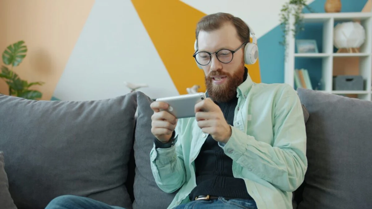 Man följer matchstatistik i mobilen hemma i soffan