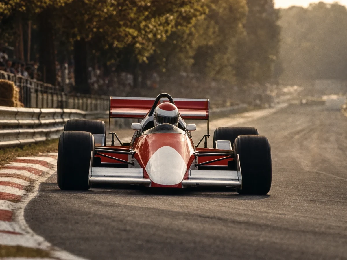 En röd och vit Formel 1-bil från slutet av 1980-talet på banan.