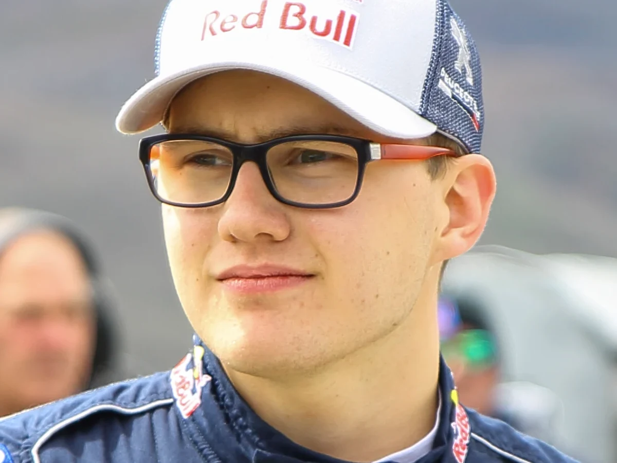 Rallycrossbil kastar upp grus i en tvär kurva på en blandad grus- och asfaltsbana.