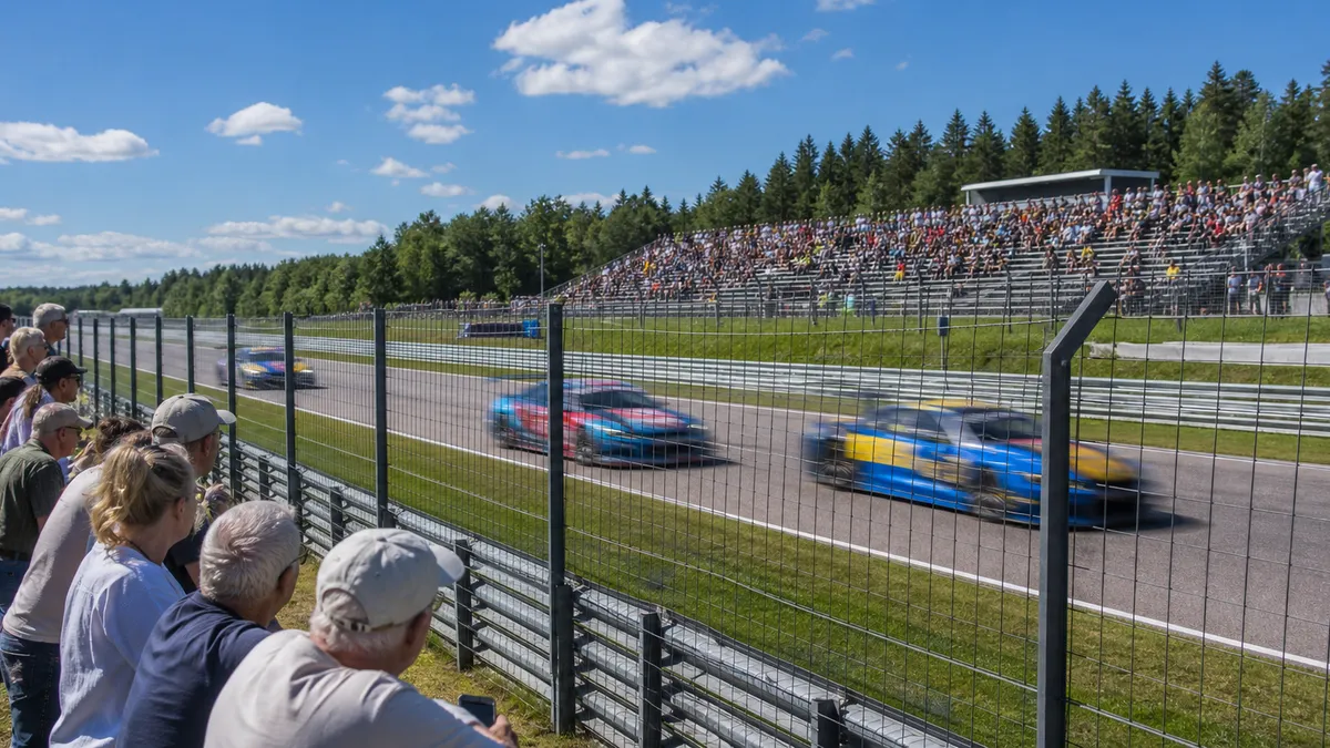 Publik längs en svensk racingbana medan tävlingsbilar passerar på banan